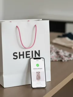 Bolsa de compras de SHEIN con un smartphone mostrando las nuevas políticas de devolución en Estados Unidos para 2025.