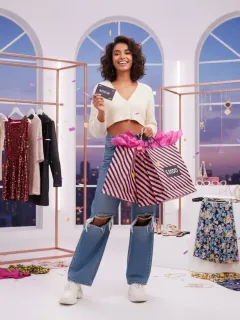 Joven feliz con bolsas de compra y tarjeta de regalo SHEIN, mostrando entusiasmo por el concurso.