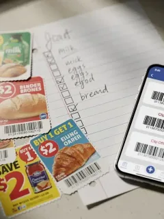 Cupones de descuento físicos y digitales junto a una lista de la compra, representando la planificación para ahorrar en supermercados.