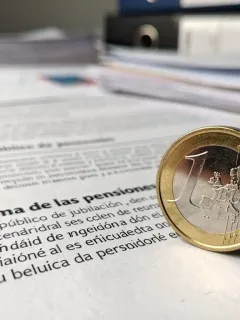 Monedas de euro sobre un documento de reforma de pensiones en España