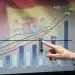 Gráfico financiero mostrando la reducción del déficit público español hacia el 3% en 2026, con la bandera de España de fondo.